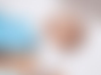 Baby on a white bed, wearing a white outfit, being examined by a doctor with blue gloves using a stethoscope. Baby looks calm. Joyful Seeds Paediatric and Developmental Clinic located in Bukit Timah