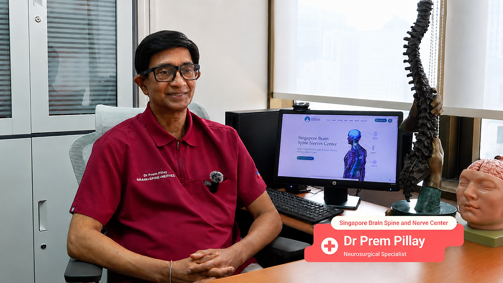Dr Prem Pillay, Senior Consultant Neurosurgeon at Singapore Brain Spine Nerves Centre, sitting at his clinic desk next to a spine model and a monitor displaying the clinic website.