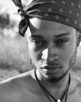 Un homme arborant un bandana et un collier, illustrant une mode audacieuse et originale.