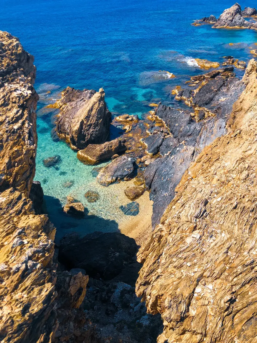 Azur cove jagged coastal cliffs above turquoise water under sunlight, fine art photographic print by Maxime Guengant.