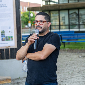 Juan Angel Chavez wears tortoiseshell glasses and holds a microphone