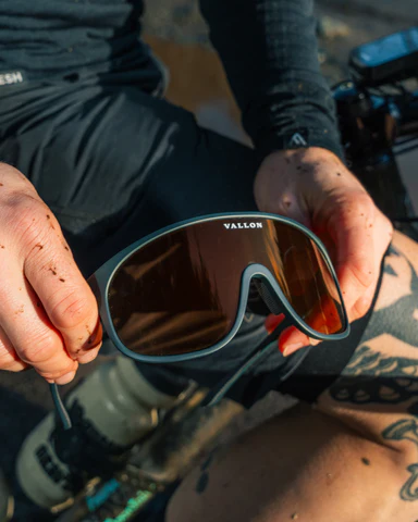 A close-up shot of a cyclist holding the Vallon Watchtowers sunglasses