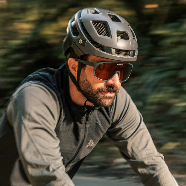 A close-up of a gravel bike cyclist riding wearing the Vallon Watchtowers sunglasses