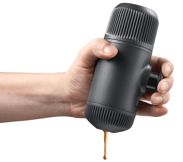 Hand operating the Wacaco Nanopresso portable espresso maker, pouring coffee from the spout.