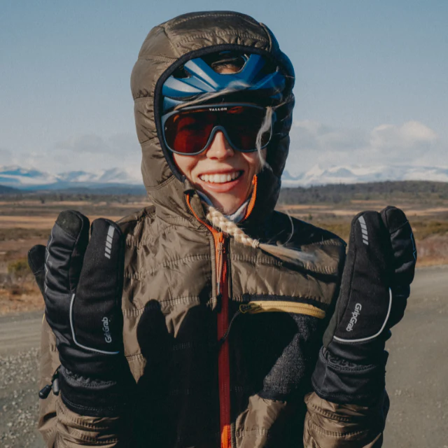 A portrait shot of a woman wearing deep winter gear with her hood up, deep winter mits and the Vallon Watchtowers sunglasses