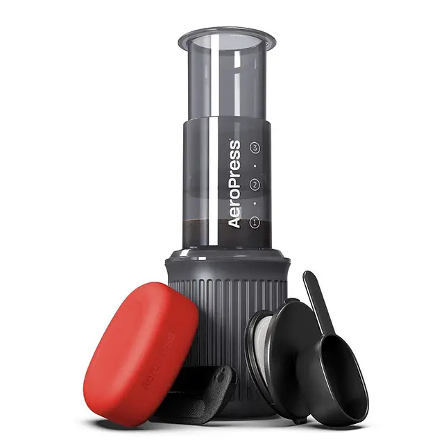 AeroPress Go travel coffee maker set with its red storage cup, plunger, filter cap, scoop, and stirrer arranged neatly.