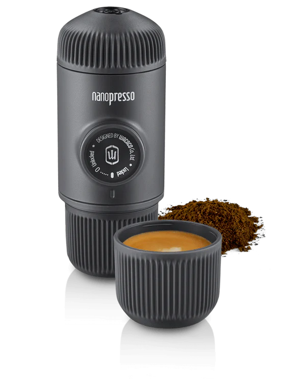 Wacaco Nanopresso espresso maker next to a shot of brewed espresso and ground coffee.