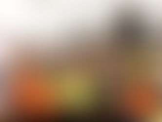 Workers in hard hats discuss plans at a construction site. One points to a document. Industrial machinery and cranes fill the background.