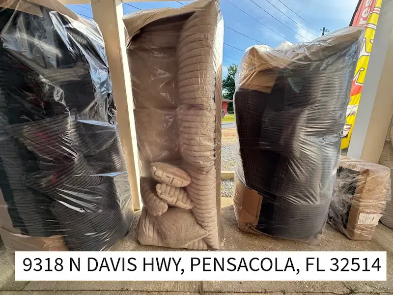 Plastic-wrapped coils of black and beige hoses on a concrete floor. Address text: 9318 N Davis Hwy, Pensacola, FL 32514. Clear sky.