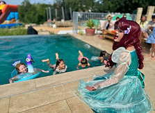 The mermaid Princess singing to children in a pool