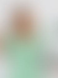 a smiling woman in a green polka dress holding a laptop balancing a green calculator