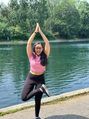 Woman holding a Tree Pose outdoors at Parc La Fontaine, smiling brightly with one leg lifted and arms raised...radiating joy, balance, and carefree energy.