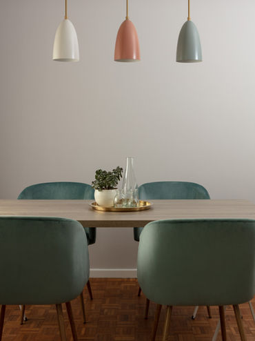 modern dining table and four green chairs, three downlighting pendants lights in muted colours hang above