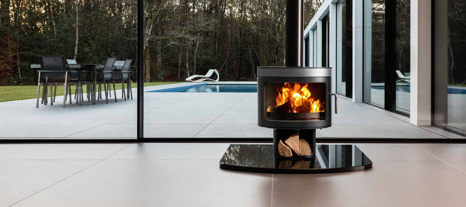 Brand photographer Simon Eldon, modern wood burning stove in modern living room with large glass sliding doors. A patio and swimming pool are outside, it is winter