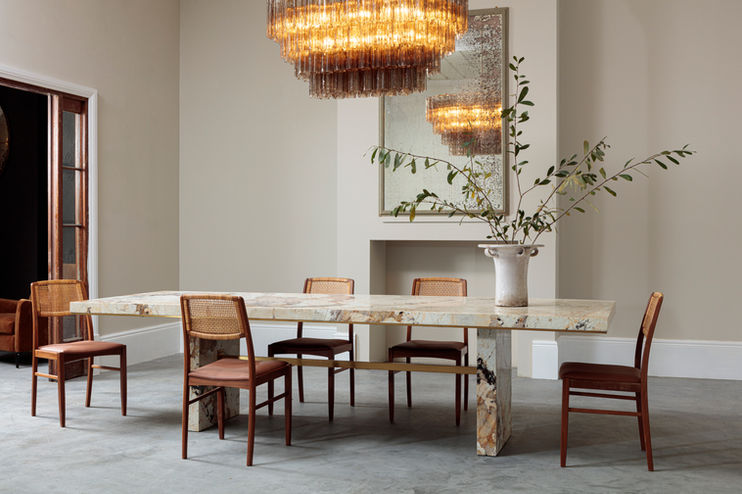 modern marble dining table and six chairs displayed in a bright neutral room with high ceilings and an amber glass chandelier, room set photoshoot by furniture photographer Simon Eldon