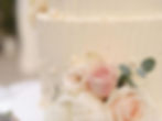 Buttercream wedding cake with pink roses and eucalyptus and pearls.
