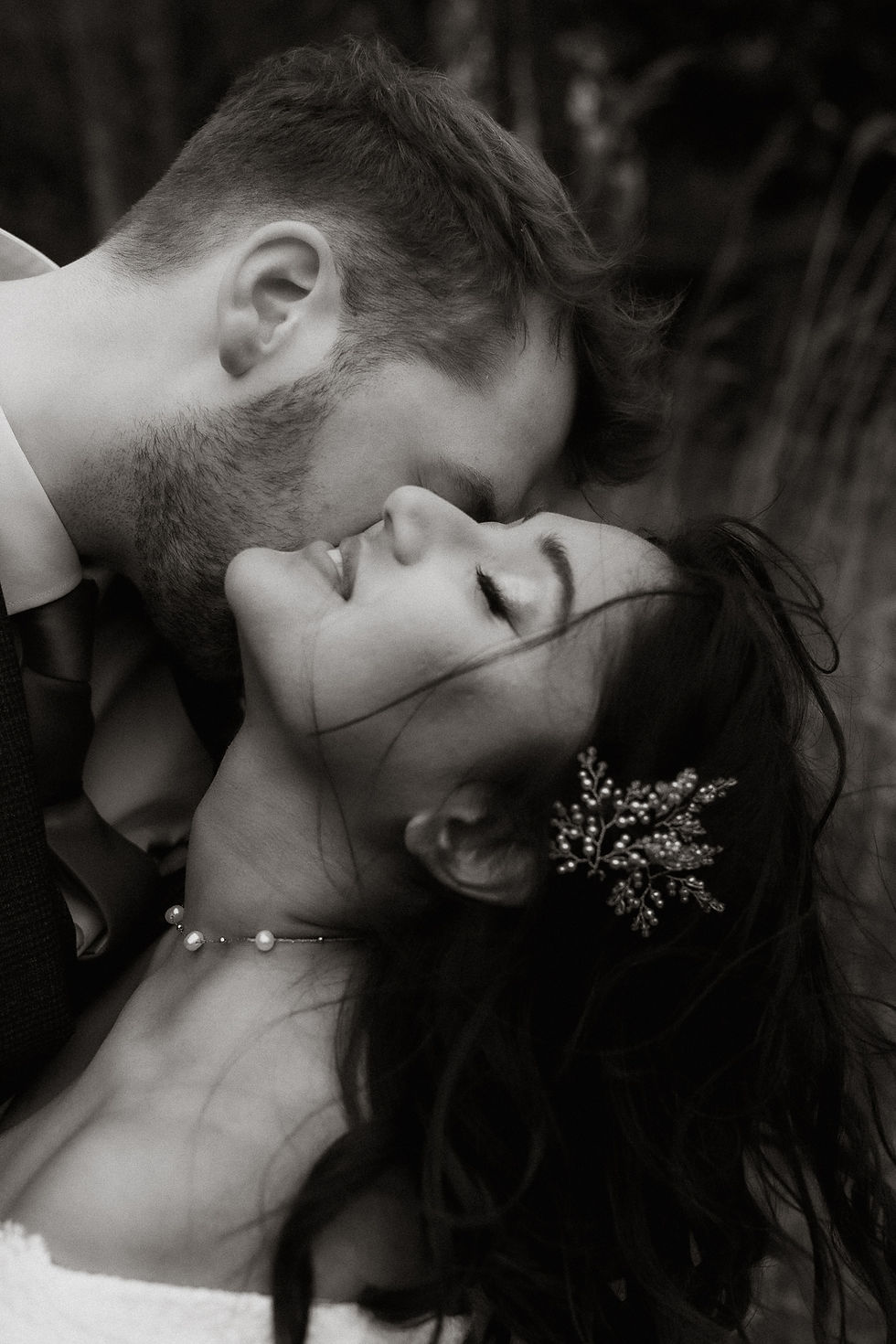 bride and groom on their wedding day during their portrait session kissing in the wind.