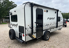 Sportsman's RV Rentals camper set up at campsite towed by SUV