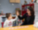 A child and a behaviour interventionist smiling, looking at each other, and giving a high five.