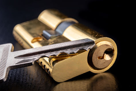 A close-up view of a key and a lock cylinder, removed from a knob to be rekeyed, showcasing their intricate metallic details.
