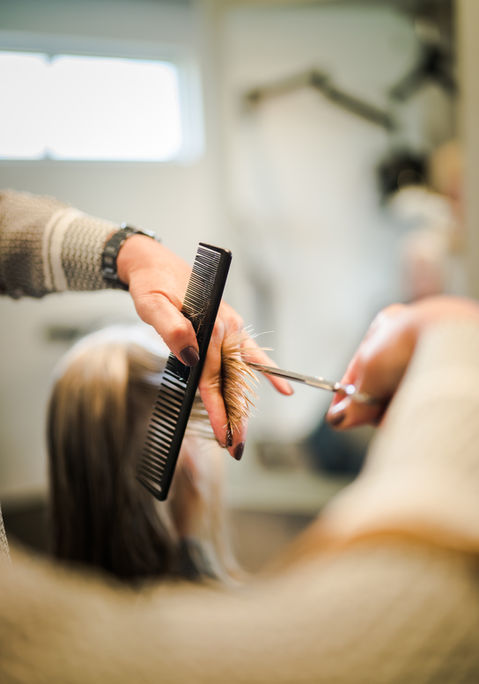 A salon stylist cuts a client's hair