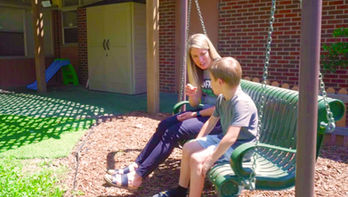 Woman and child talking on an outdoor swing