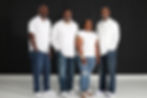 Four smiling family members standing together in white shirts.