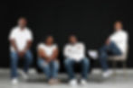 Smiling Black family of four in white tops and jeans.