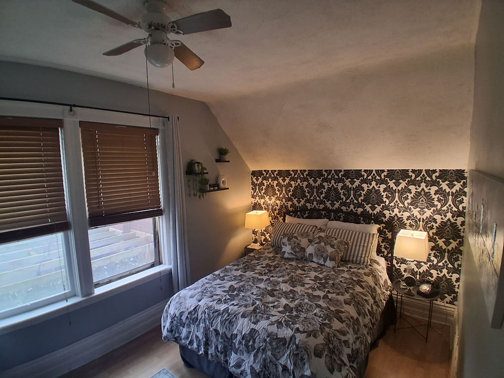 Bedroom with patterned bed, wallpaper, and windows