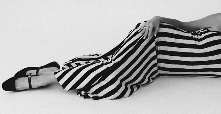 Person in a striped dress reclining with smooth skin.