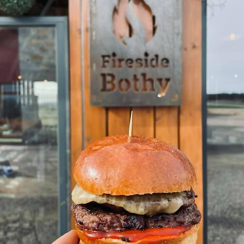 Holding a burger in front of restaurant metal sign