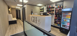 Modern reception desk with illuminated GHB branding and retail shelves in a salon interior