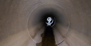 High pressure water jetting nozzle clearing debris inside a dark drainage pipe