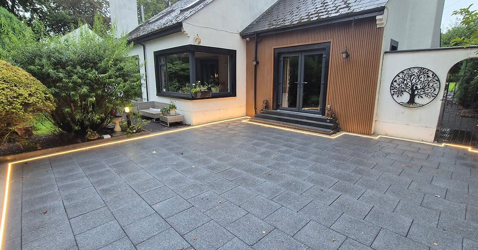 Wide view of freshly cleaned grey block paved patio seating area outside a residential home