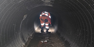 Drainage operative wearing safety harness and gear preparing for a confined space entry