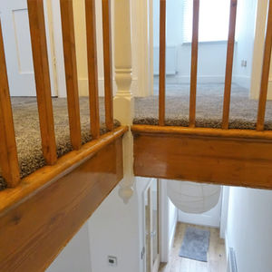 Spacious empty room with wooden flooring, white walls, and a ceiling light
