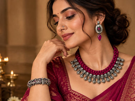 Woman wearing a ruby-coloured braided thread necklace, vintage oxidised silver earrings with ruby-red stones and an ethnic silver bracelet, styled with a burgundy saree for Karwa Chauth.