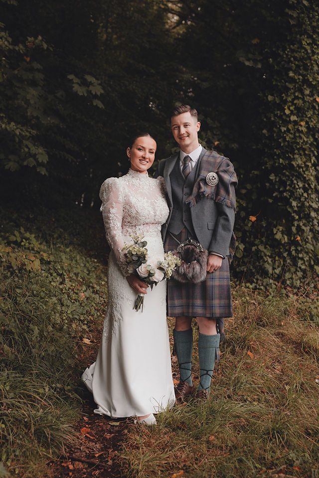 Bride and groom embracing in moody Scottish countryside scenery