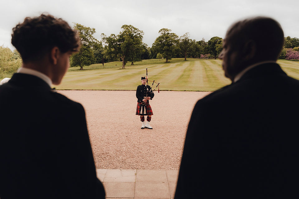 Groom in traditional Scottish kilt adjusting jacket before ceremony, captured at Dundas Castle by Garrigós & Golebiowski.