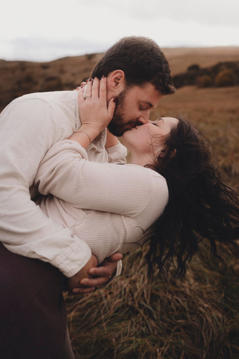 Romantic couple portrait at sunset in Holyrood Park, Edinburgh, cinematic style, natural light, capturing genuine connection and fine art storytelling