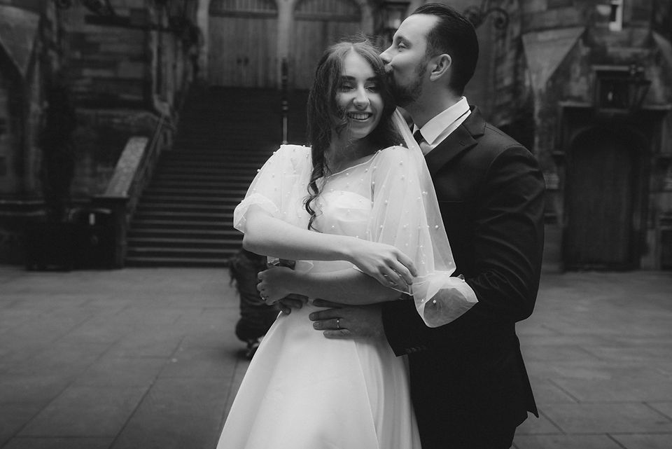 Romantic wedding elopement in front of the majestic walls of New College, Edinburgh, photographed by a professional wedding photographer.