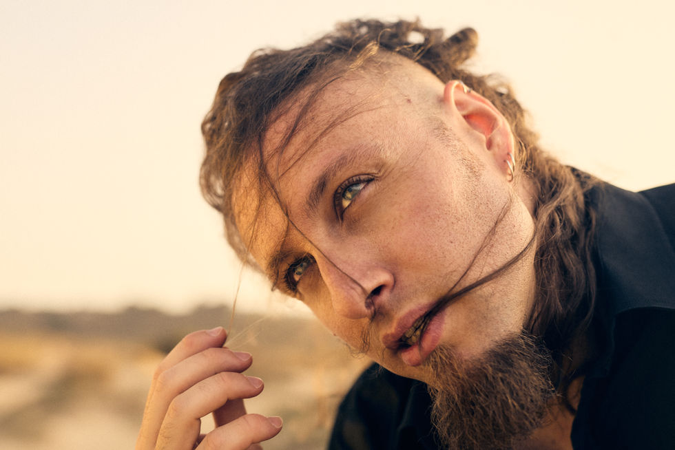 Professional beach photoshoot of a musician, artistic portrait with natural light for music promotion and personal branding.