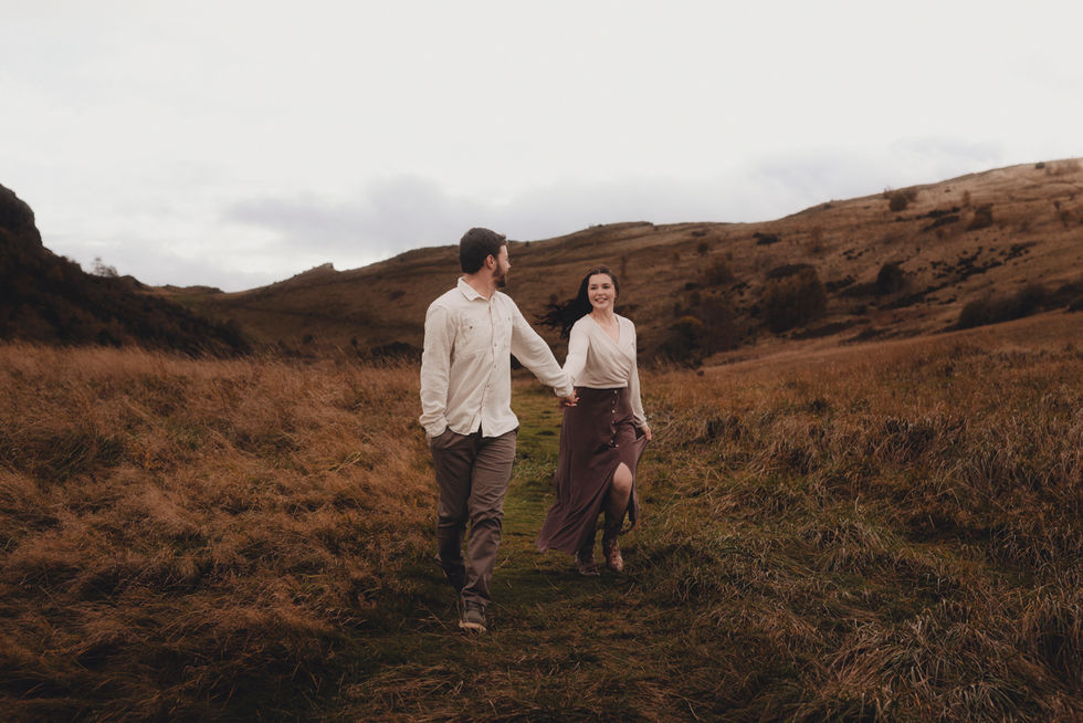 Romantic couple portrait at sunset in Holyrood Park, Edinburgh, cinematic style, natural light, capturing genuine connection and fine art storytelling