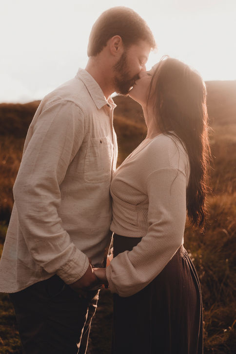Romantic couple portrait at sunset in Holyrood Park, Edinburgh, cinematic style, natural light, capturing genuine connection and fine art storytelling