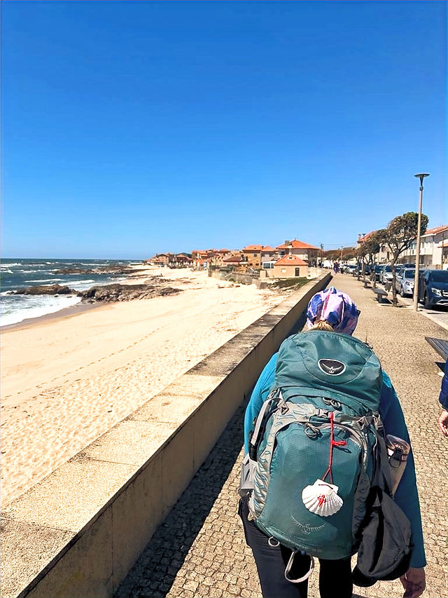 woman walking with backpack along ocean