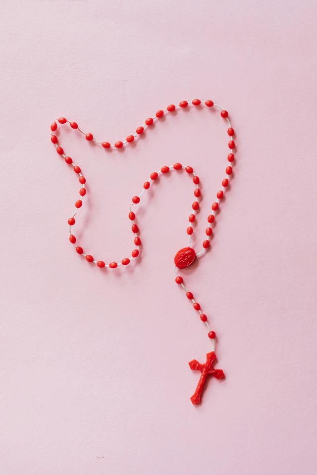 red rosary on pink surface