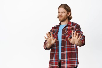 Free photo no thanks. displeased blond bearded man shaking hands and grimacing from dislike, aversion, rejecting, refusing smth, standing over white background.