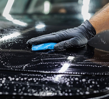 Worker clean car body with blue clay for cleaning before applying protective layer or coat