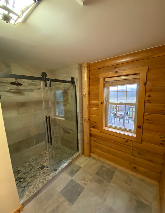 Compact bathroom with a low-threshold shower, built-in shelving, grab bar, and clean light finishes
