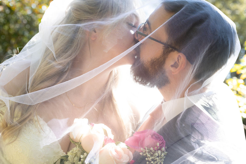 newlyweds kissing under veil